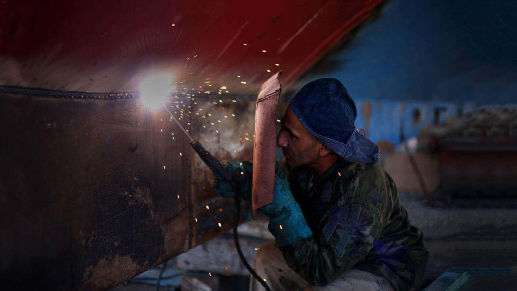 Welder using torch on metal, sparks flying